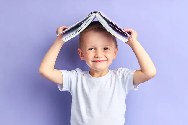 Играющий мальчик, держа книгу над головой — стоковое фото