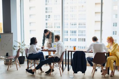 Genç çok ırklı profesyoneller iş ofisinde gündelik tartışmalara giriyorlar.