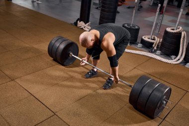 Sporcu spor salonundaki barın yanında duruyor.