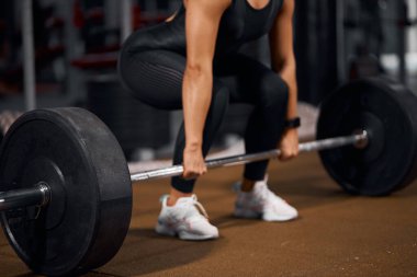 Kadın elleri halteri yerden kaldırıyor.