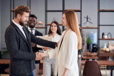 Yakışıklı sakallı lider genç bayana el sıkışıyor.