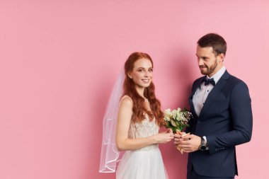 Gülümseyen nişanlı ve gelin pembe arka planda izole edilmiş