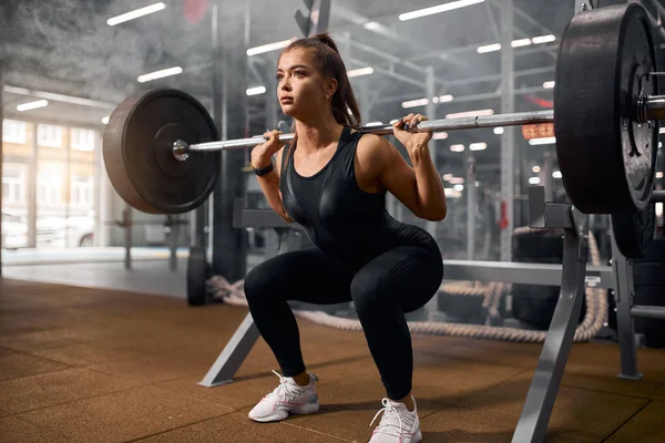 Pretty fit woman squatting with weight — Stock Photo, Image