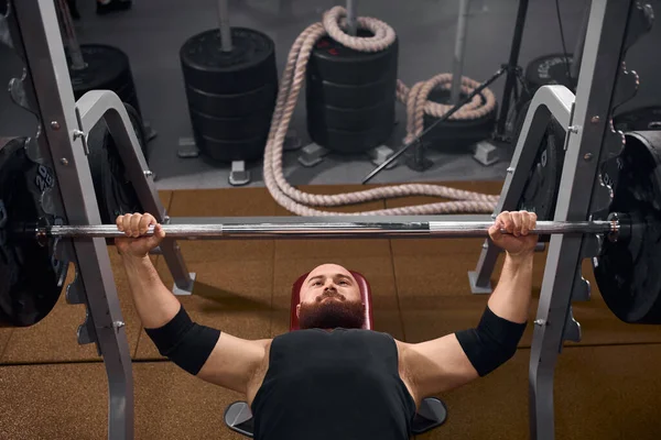 Homme musclé couché sous l'haltère — Photo