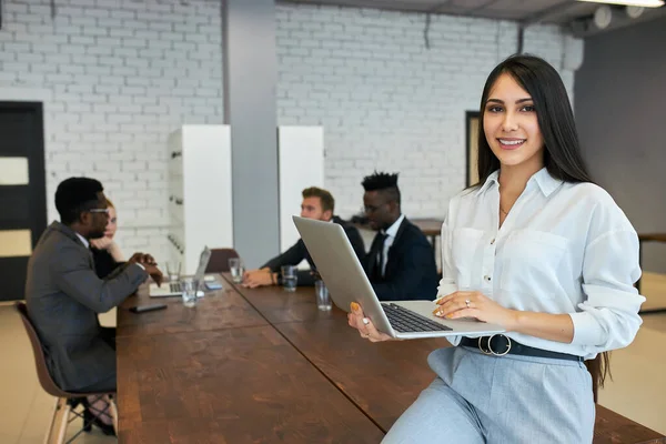 Glimlachende jonge vrouw in formele kleding zitten op tafel met behulp van laptop — Stockfoto