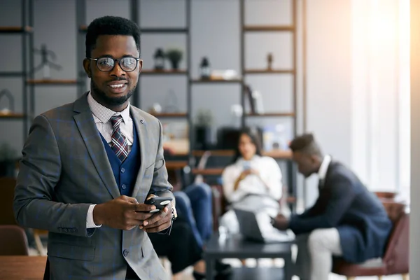 Knappe jonge Afrikaanse man met behulp van mobiele telefoon tijdens het werk — Stockfoto