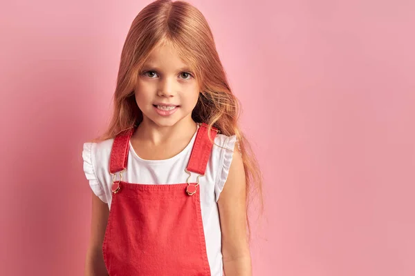Portré csinos kislány hosszú haj a rózsaszín háttér — Stock Fotó