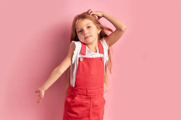 Niña reflexiva en mono rojo aislado sobre fondo rosa —  Fotos de Stock