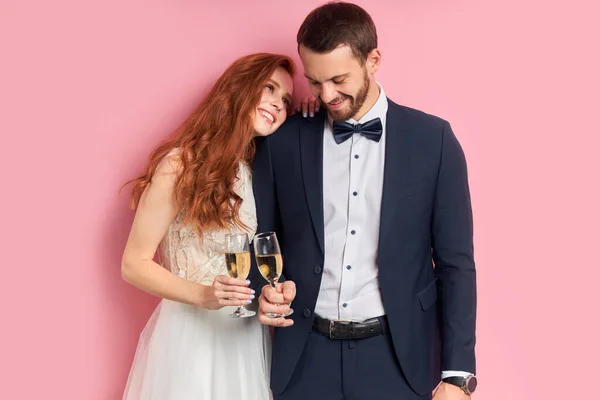 Lovely couple wearing white dress and tuxedo holding glass of champagne — Stock Photo, Image