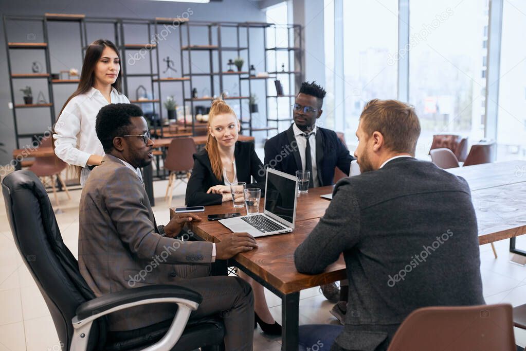 International group of business people sit together at table