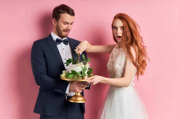 Surprised man holding cake and woman in dress isolated