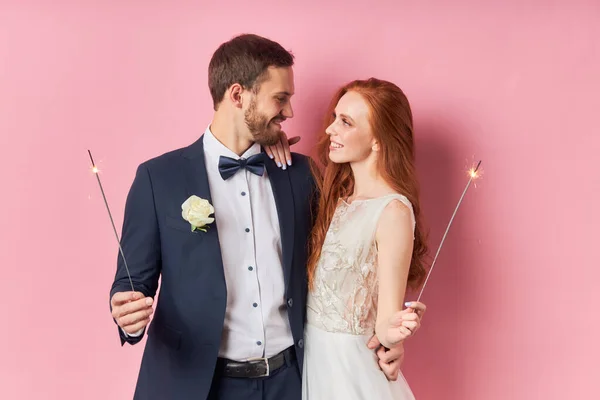 Jovem casal caucasiano com fogo de bengala isolado sobre fundo rosa — Fotografia de Stock