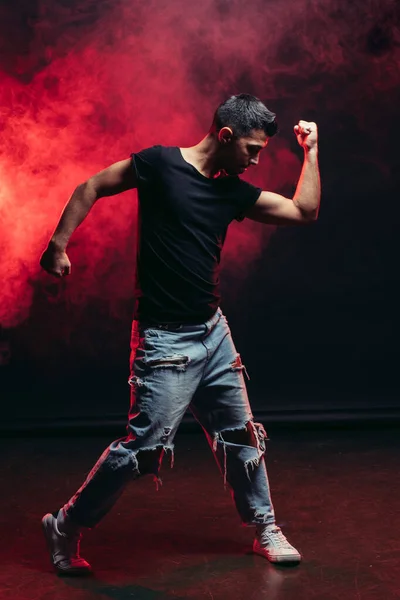 Bonito jovem masculino dança isolado no vermelho fumegante espaço — Fotografia de Stock