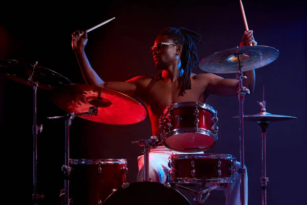 Hombre africano activo tocando la batería en luces de neón —  Fotos de Stock