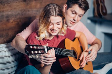 Evde dinlenip gitar çalan hoş bir çift.
