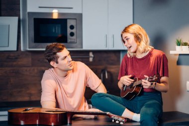 Evde ukulele çalan kendini yetiştirmiş bir kadın.