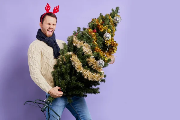 Mann in rotem Weihnachtshorn hält Weihnachtsbaum — Stockfoto