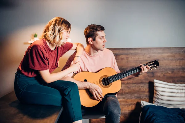 Dos jóvenes amigos positivos se sientan tocando la guitarra y escuchan — Foto de Stock