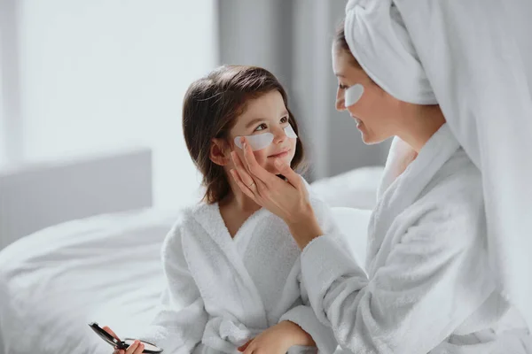 Opatrní matka a dcera používat obličejové náplasti pod očima — Stock fotografie
