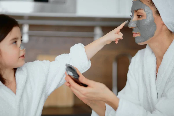 Mooie ouder en zijn dochter zitten in keuken met gezichtsmaskers — Stockfoto