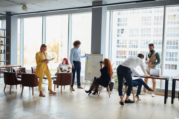 Fiatal kaukázusi üzletember előadást tart flipchart-on a modern irodai munkatársak csoportjának — Stock Fotó