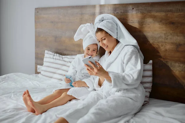 Young caucasian mother with daughter use smartphone — Stock Photo, Image