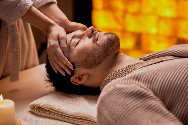 Vista lateral en guapo barbudo caucásico hombre recibiendo masaje en la cabeza en el salón de spa —  Fotos de Stock
