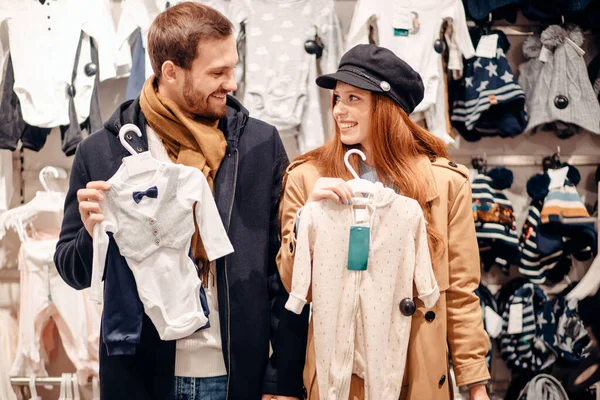 young caucasian couple together in search of clothes for newborn baby