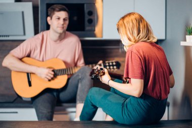 Beyaz adam evde genç bir kız için gitar çalıyor.