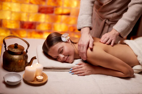 Relajada caucásica sonriente mujer recibiendo masaje de espalda en el spa —  Fotos de Stock