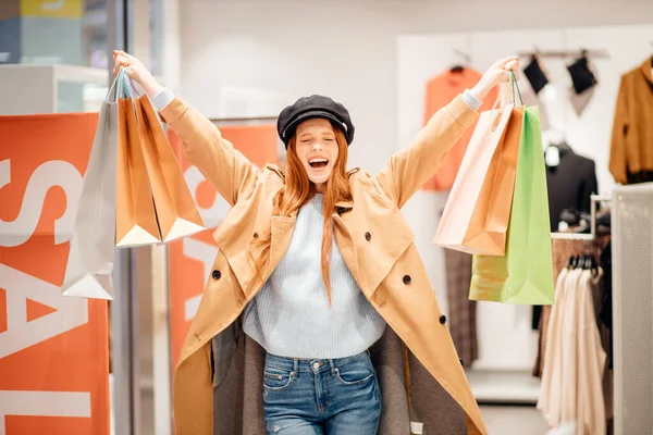 Vrolijke vrouw het verhogen van de handen met papieren tassen na het winkelen — Stockfoto
