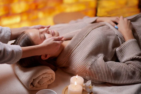 Jeune femme bénéficiant d'un massage facial au salon de spa — Photo