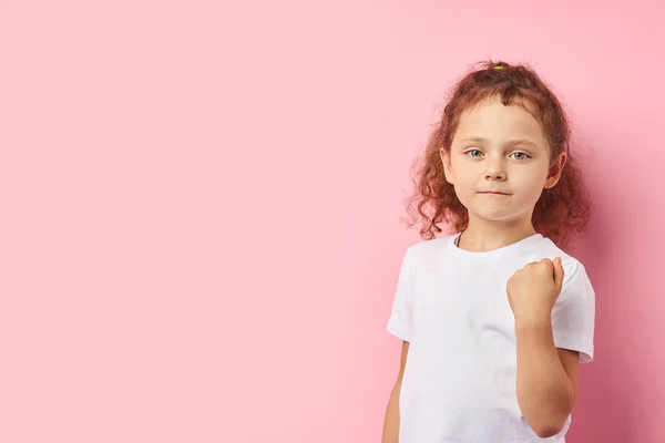 Hazardous girl 5-6 years with curly red hair isolated over pink background — Stock Photo, Image