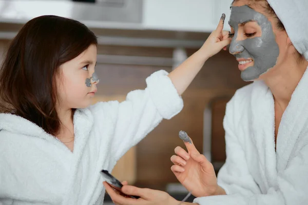 Kind sitzt mit Mutter in Maske in Küche — Stockfoto