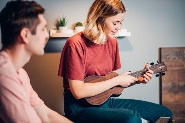 Evde ukulele çalan kendini yetiştirmiş bir kadın.