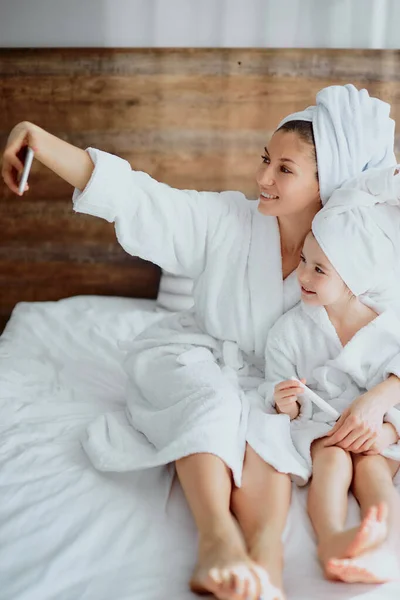 Linda hembra y su hija tomando fotos de sí mismos en la cama — Foto de Stock