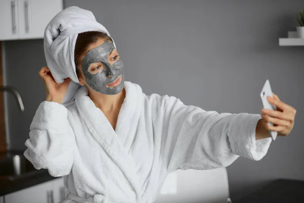 Krásná žena s obličejovou maskou vzít selfie v ložnici — Stock fotografie