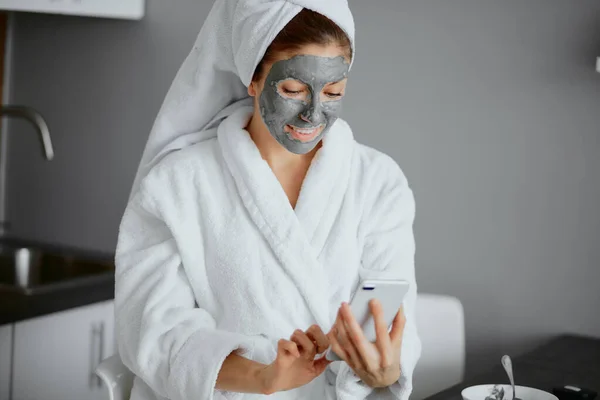 Belle femme caucasienne en peignoir blanc et serviette utiliser des masques de beauté — Photo