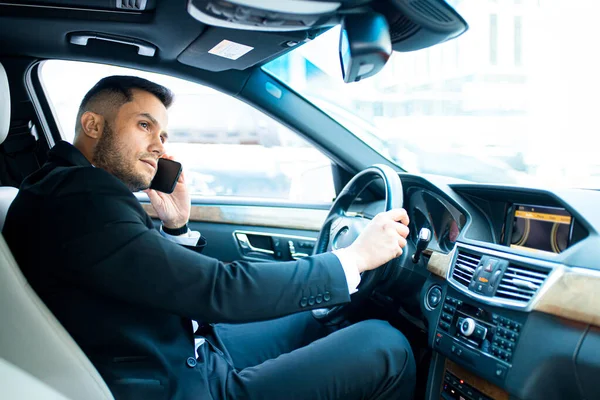 Hombre de éxito hablar por teléfono con su colega de negocios, mientras que montar en coche — Foto de Stock