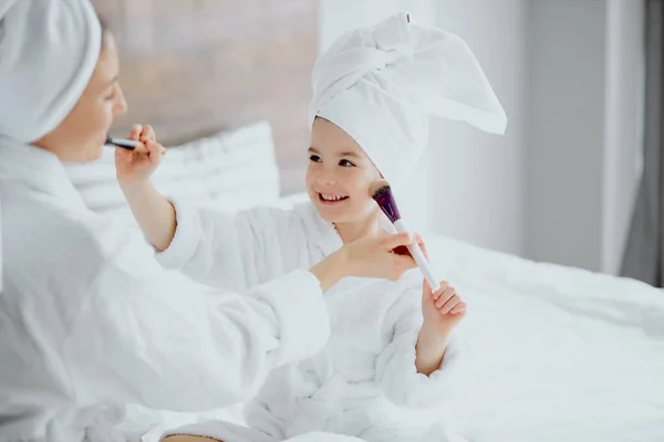 Awesome woman with daughter sit holding make-up brushes — Stock Photo, Image