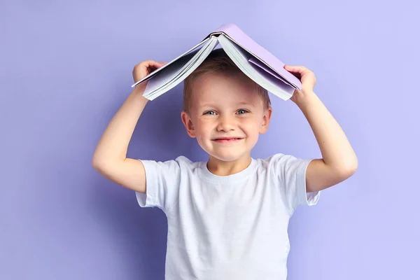 Счастливый мальчик с книгой над головой — стоковое фото