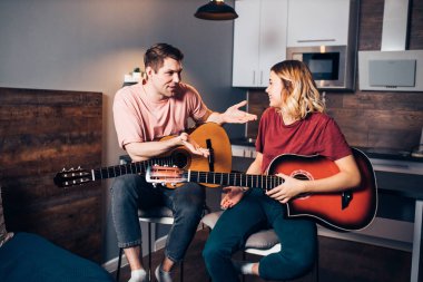 Genç çift evde gitar çalarken konuşuyor.