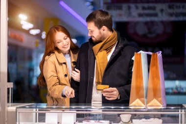 Mutlu, genç, romantik çift mücevher dükkanından altın yüzük alıyor.