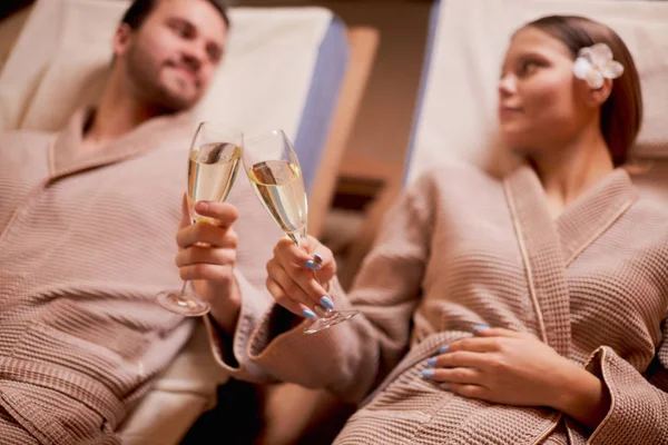 Молодая супружеская пара в спа-салоне пьет шампанское — стоковое фото