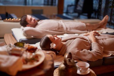 Spa ve sağlık merkezindeki masaj yataklarında yatan çift.