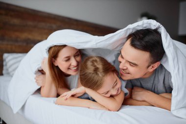 Evde battaniyenin altında neşeli, pozitif bir aile