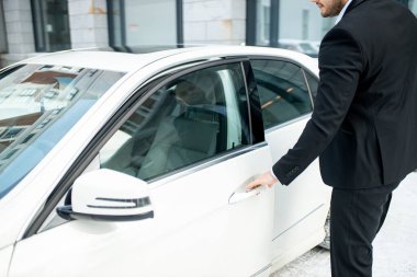 Yönetici arabasının kapısını açan adamın görüntüsü.