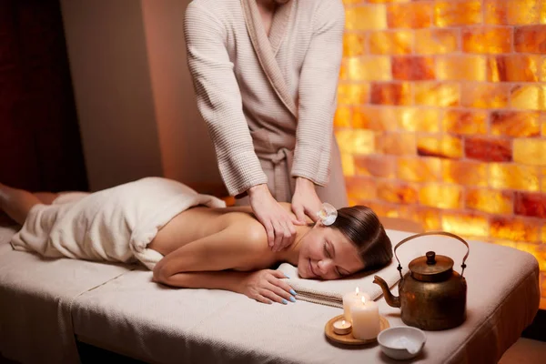 Massagista feminina fazendo massagem no ombro feminino no salão de beleza — Fotografia de Stock