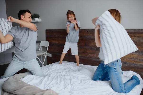 Jovem família caucasiana lutando com travesseiros — Fotografia de Stock