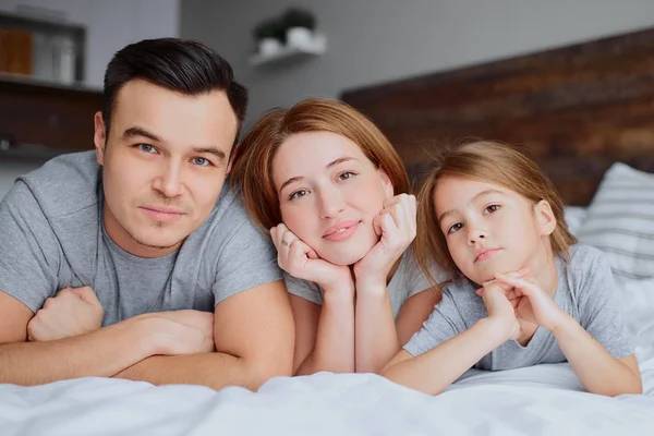 Älskar söta föräldrar med sin söta lilla flicka i sängen — Stockfoto